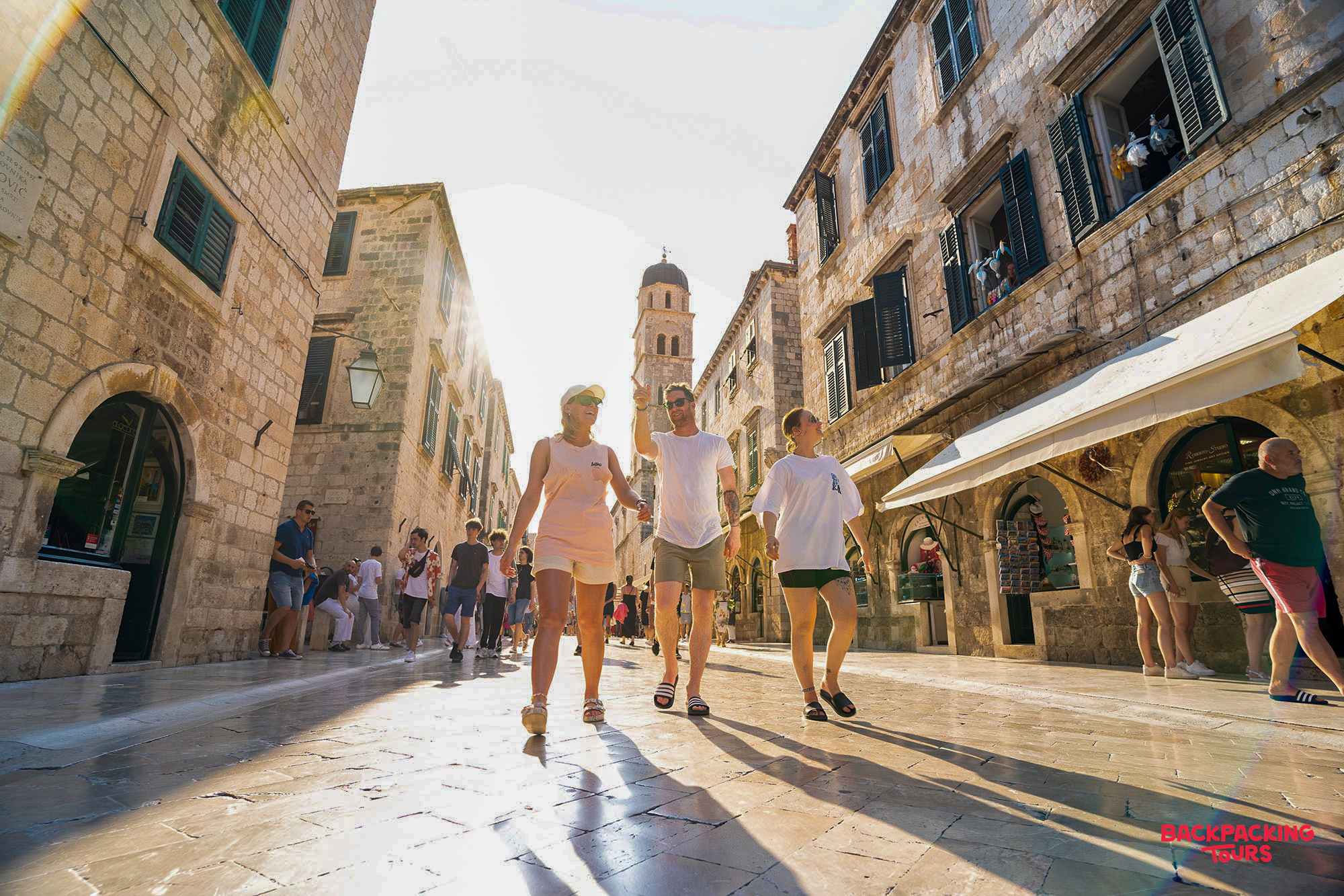 Three friends enjoy a walking tour through the sunny, historic streets of Dubrovnik Old Town.