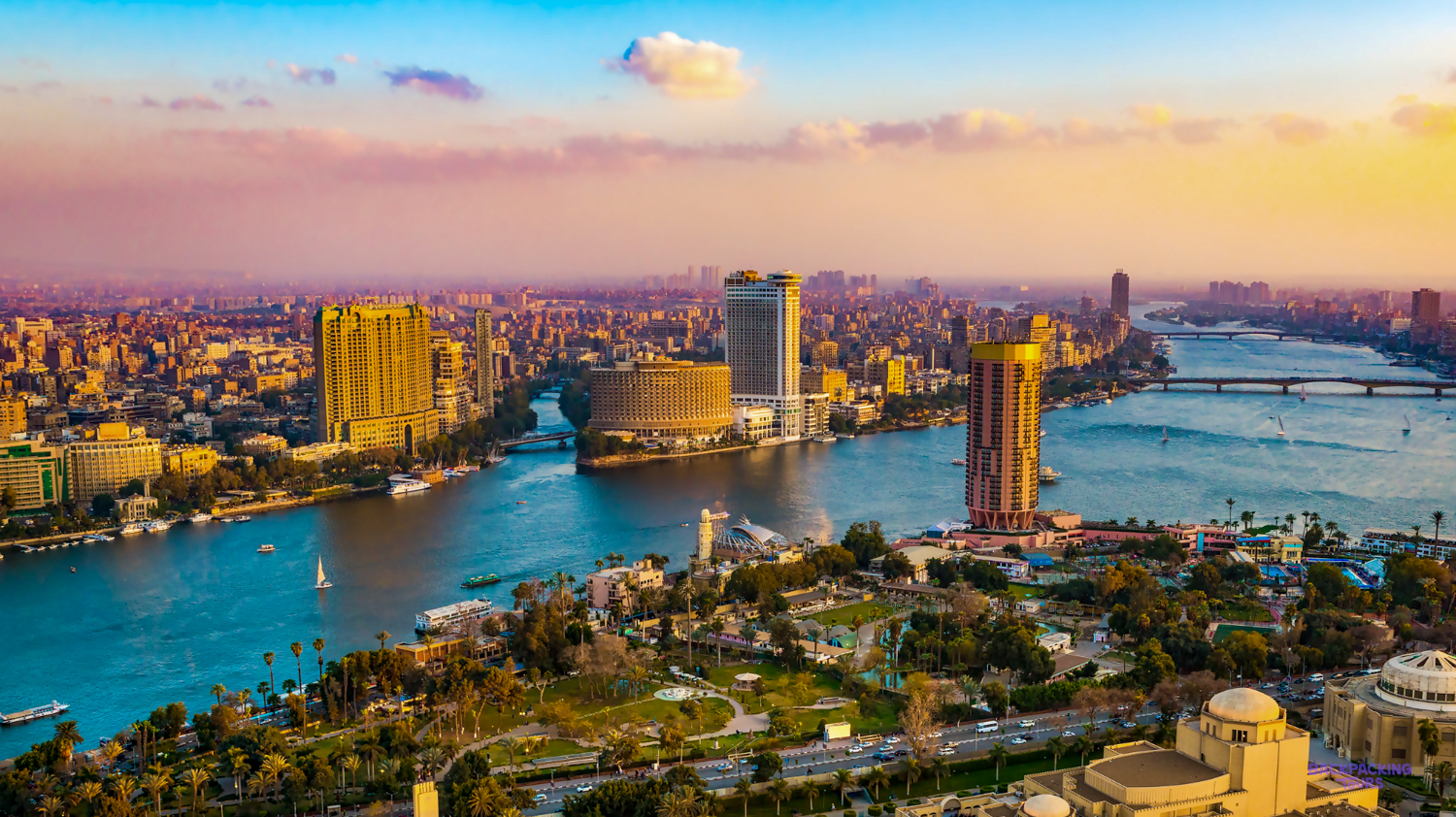 Vibrant Cairo cityscape at sunset, with the majestic Nile River flowing past modern buildings and lush green islands.