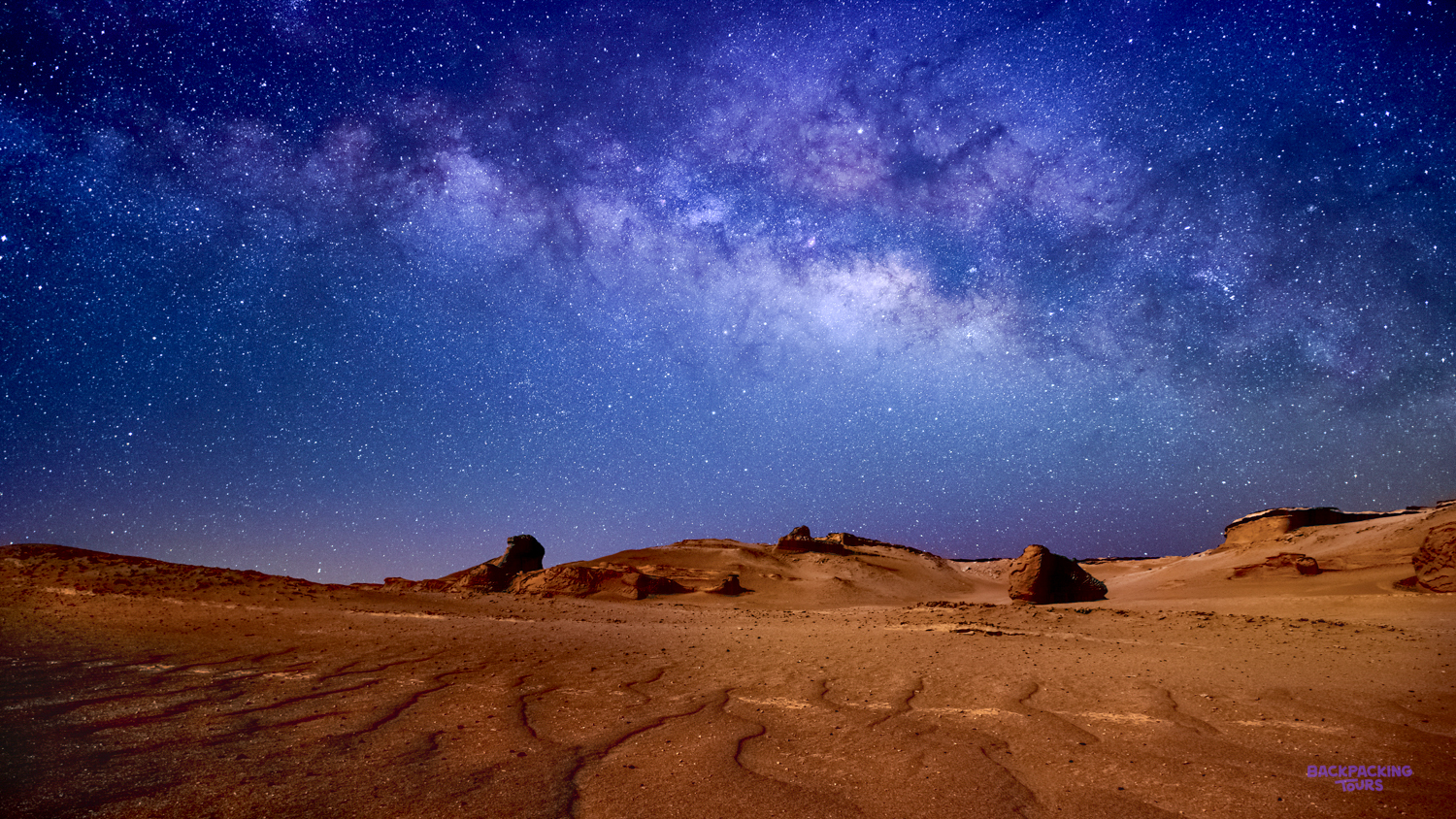 The Milky Way illuminates the vast desert landscape and unique rock formations of Wadi al Hitan.