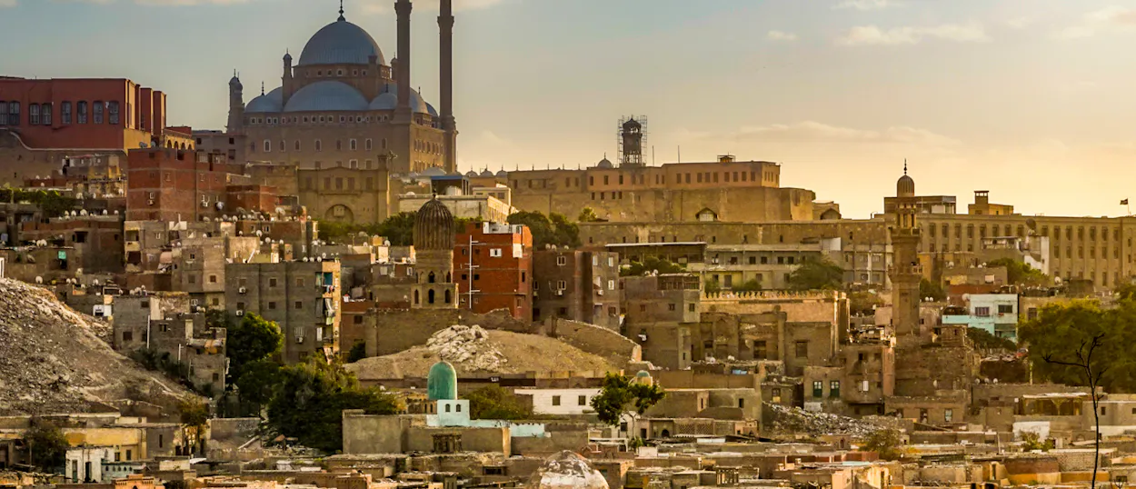 Historic Cairo cityscape at golden hour, with the Muhammad Ali Mosque and Citadel overlooking the city.
