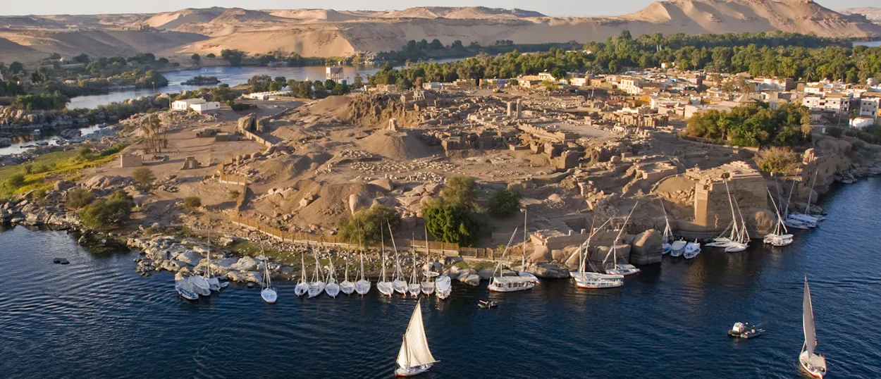 An aerial view of Elephantine Island in Aswan with ancient ruins and many sailboats on the Nile.