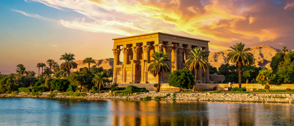 The ancient Philae Temple in Aswan, Egypt, beautifully reflected in the Nile at sunset.