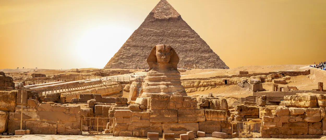The ancient Sphinx and Great Pyramid of Giza under a bright desert sky in Cairo.