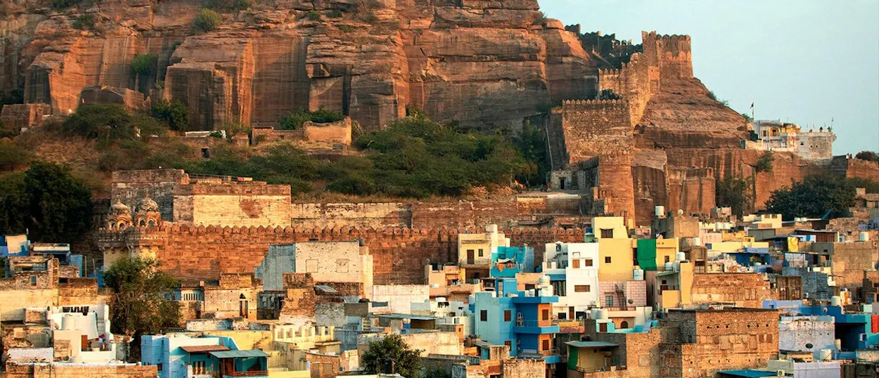 A massive stone fort with a white spire overlooks a city of blue and light-coloured buildings.