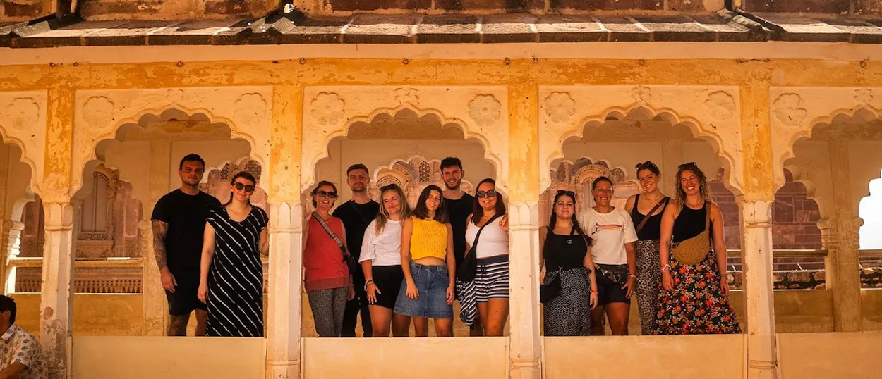A group of people smiling and posing for a photo within an old, yellow-coloured building with ornate arches.