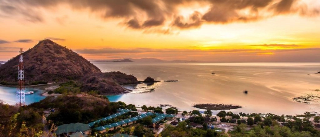 Stunning golden sunset over Labuan Bajo, with a resort town nestled by the calm bay.