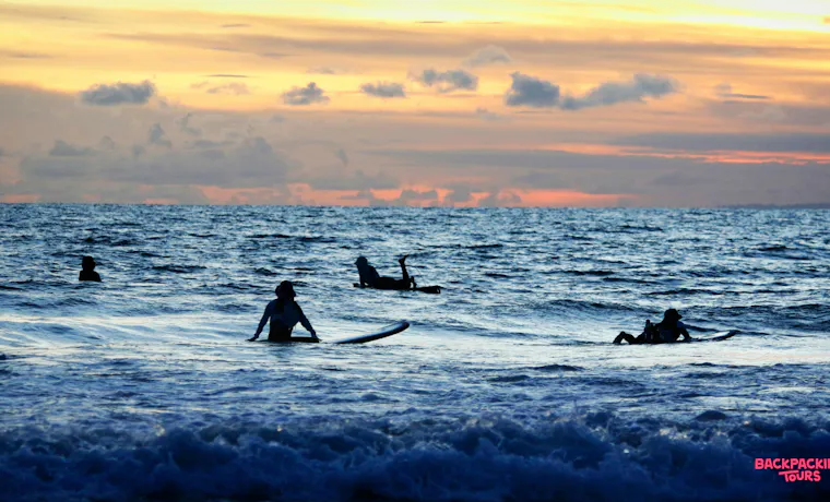 Silhouetted surfers enjoy the beautiful sunset over the calm ocean in Lombok.