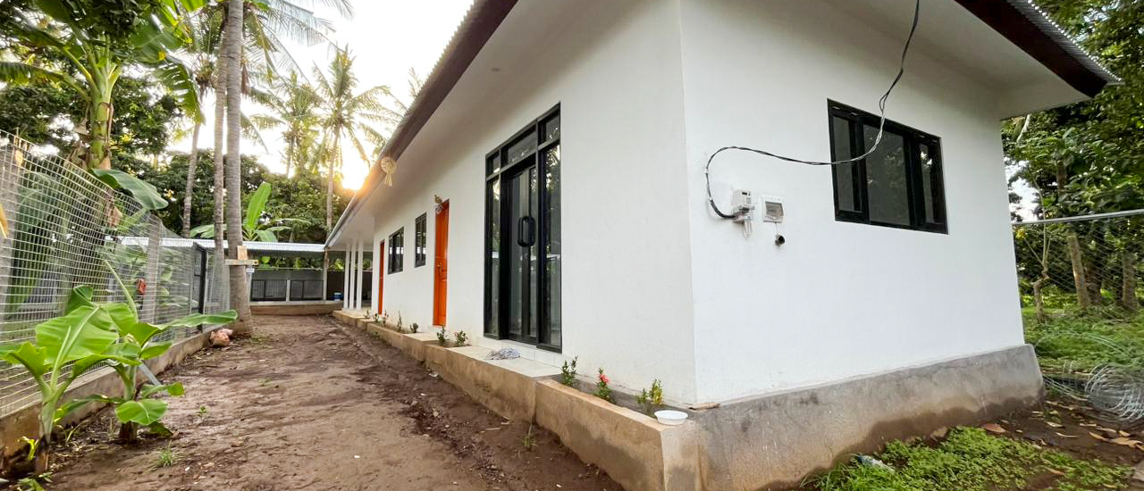 The animal care centre's white building, with orange doors, beside a garden path under palm trees.