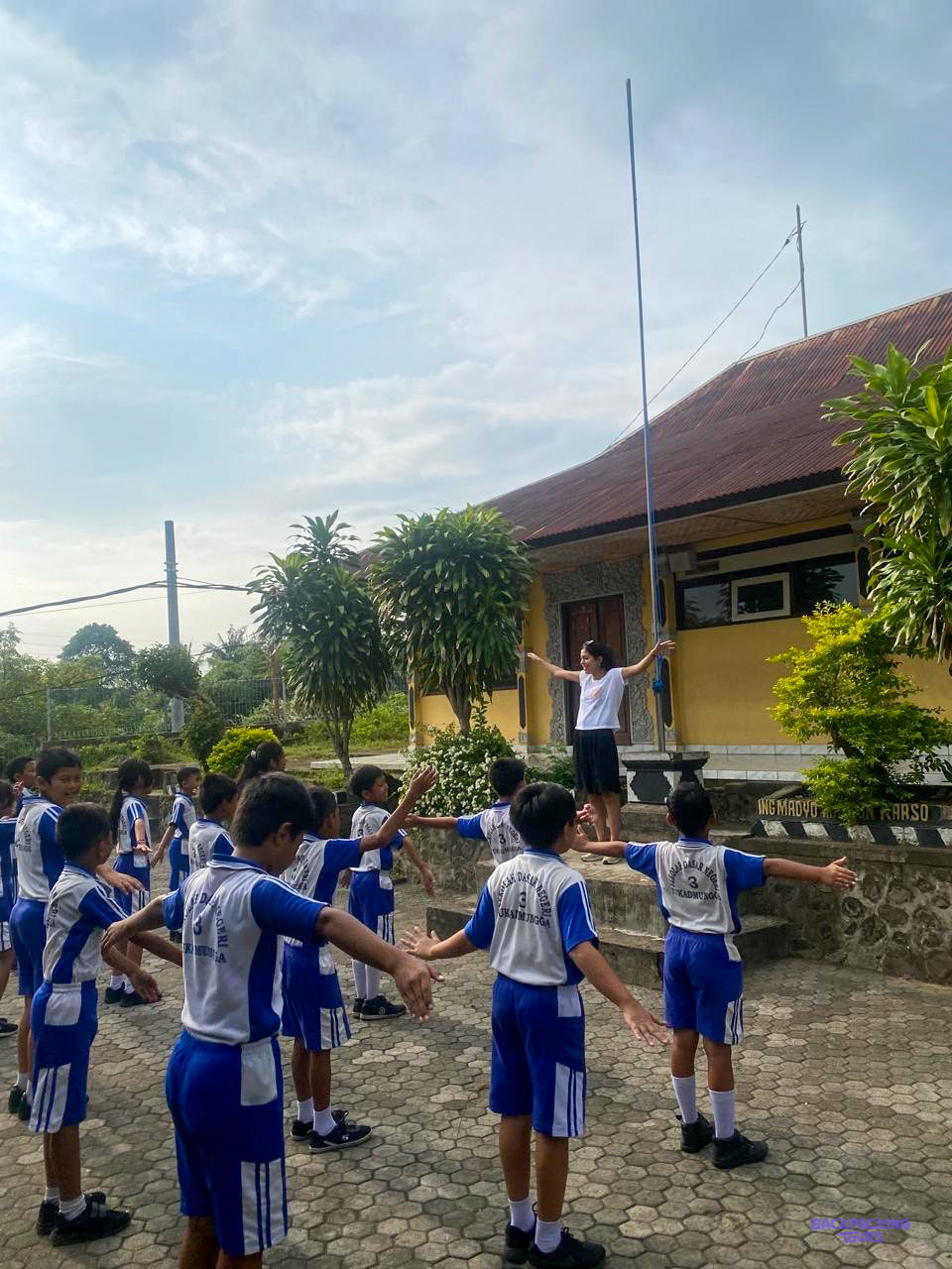 Boys in blue and white football kit hold hands in a circle in the schoolyard.