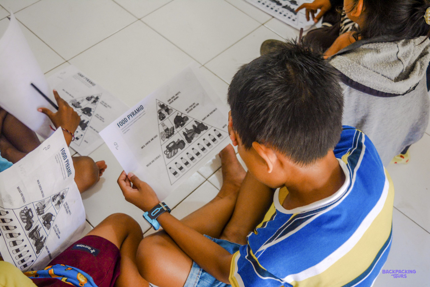 A boy studies his food pyramid worksheet during an English lesson on healthy eating.