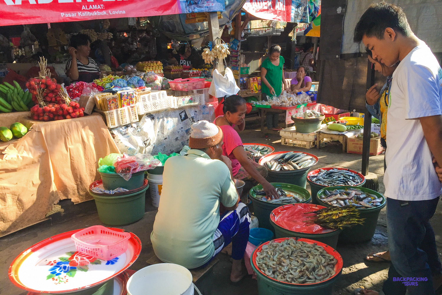 Vendors sell fresh fish and vegetables from basins at a busy stall in Lovina's market.
