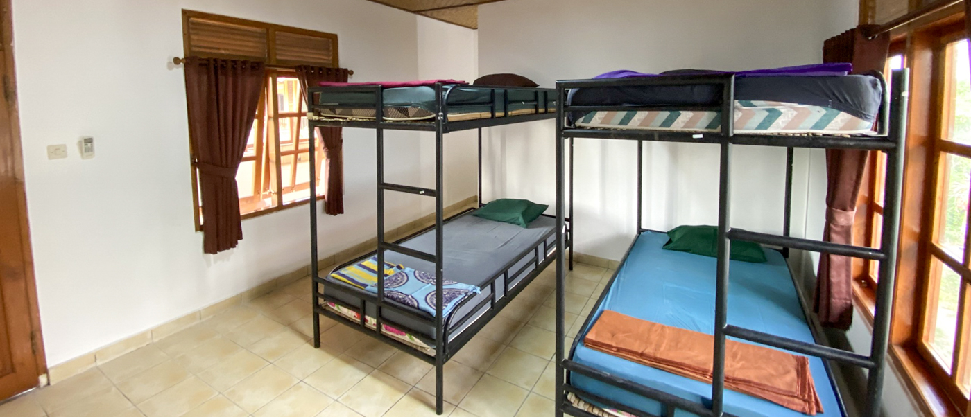 Two black metal bunk beds with fresh linen in a bright, tiled shared bedroom.