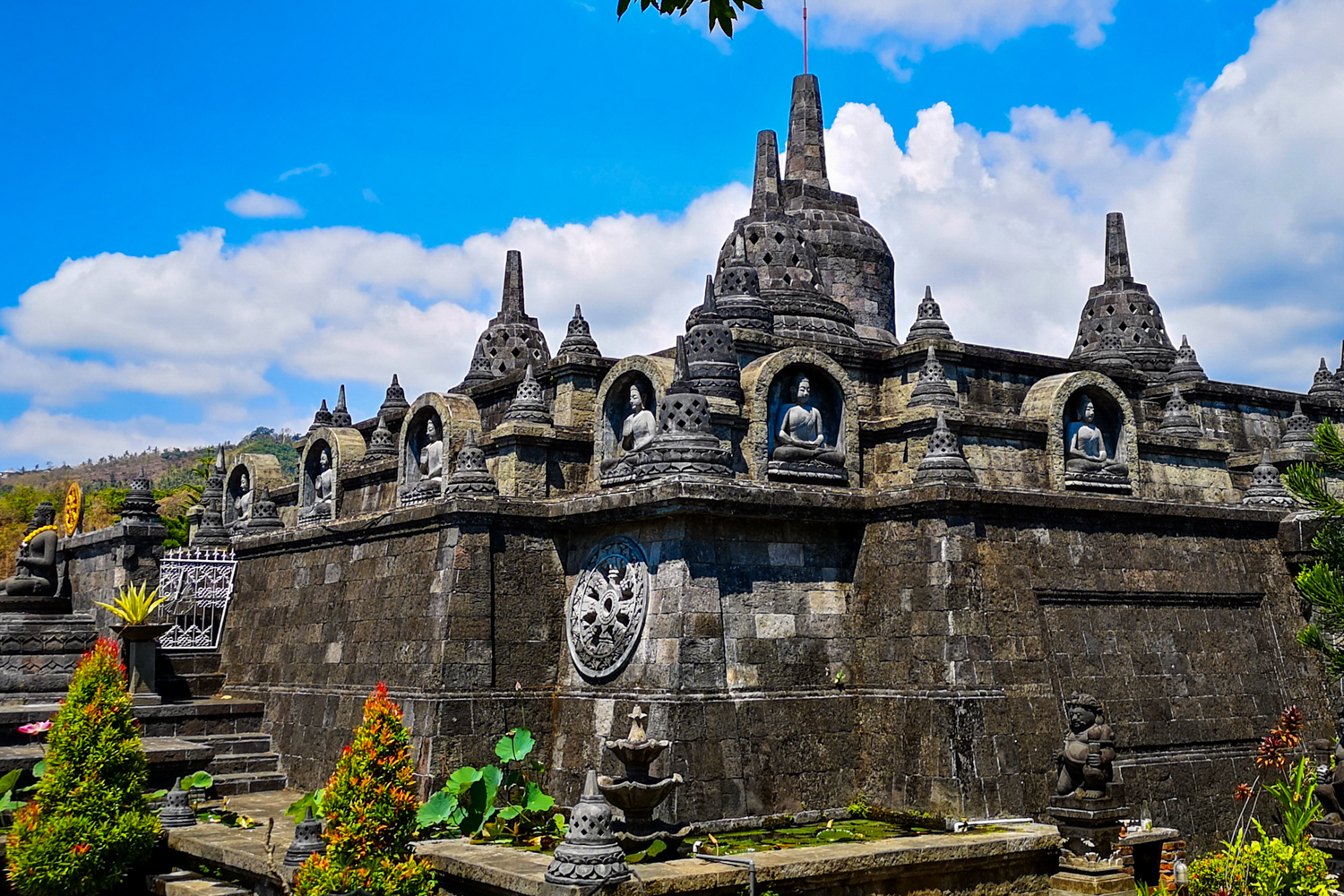 Stone stupas and seated Buddha statues on a terrace at a Buddhist monastery near Lovina.