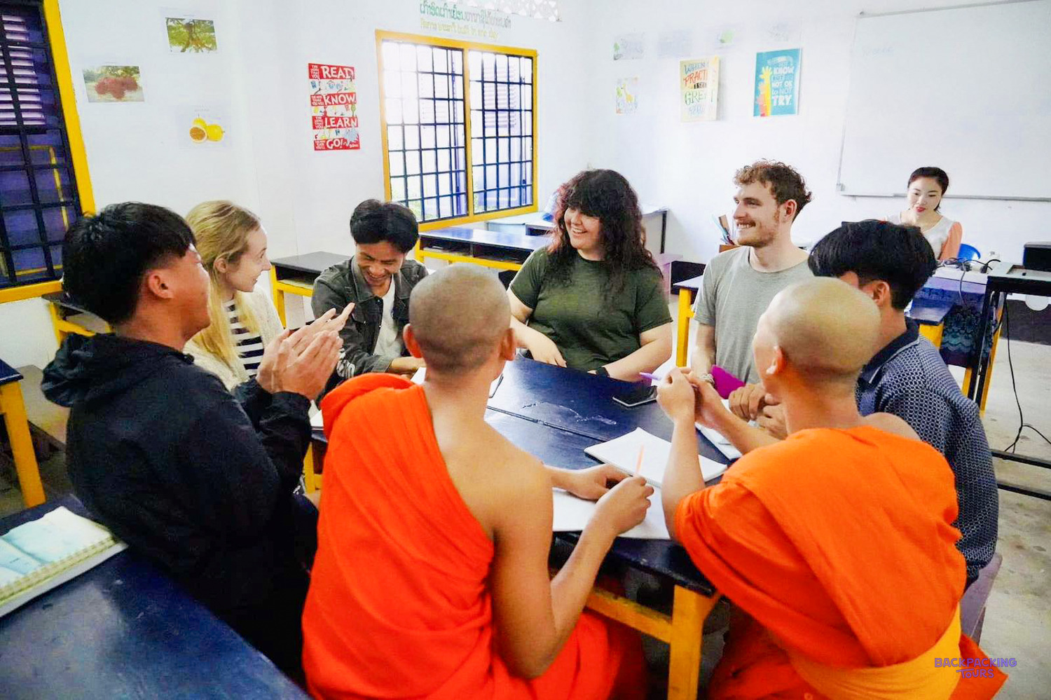 Volunteers chat across a table with young monks and Lao students during a conversation class.