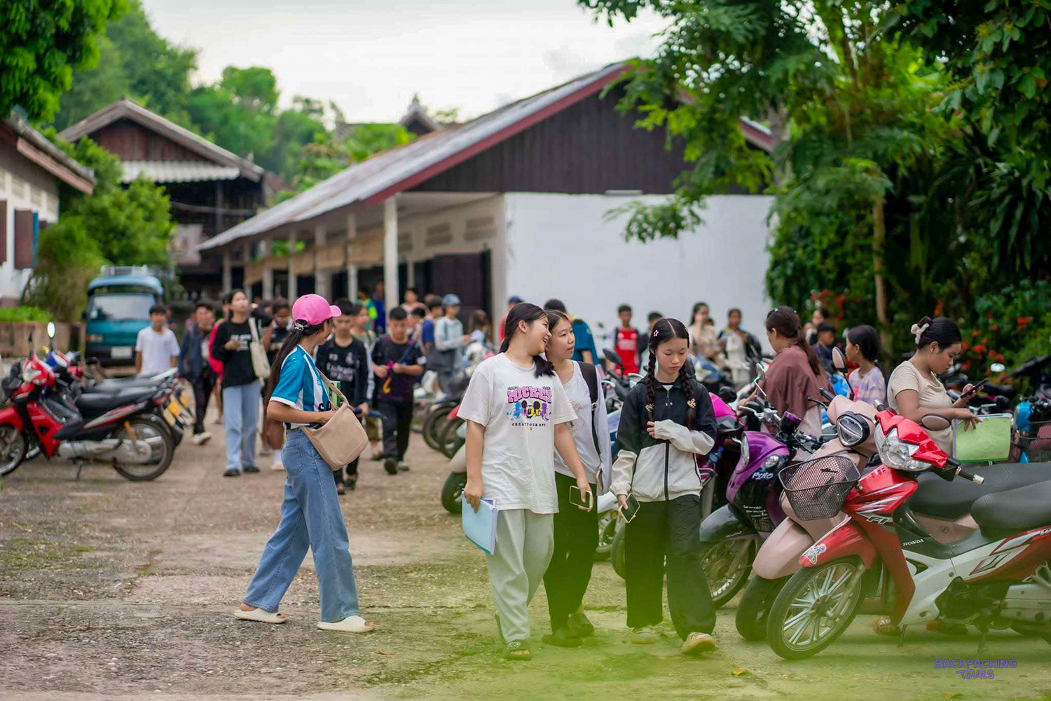 Students walk across a school yard lined with parked motorbikes in Luang Prabang.