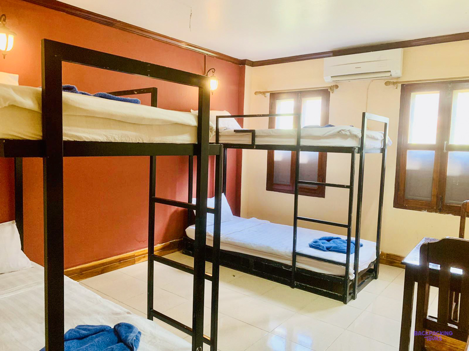 Two sets of bunk beds with fresh white sheets and folded towels in a shared volunteer room.