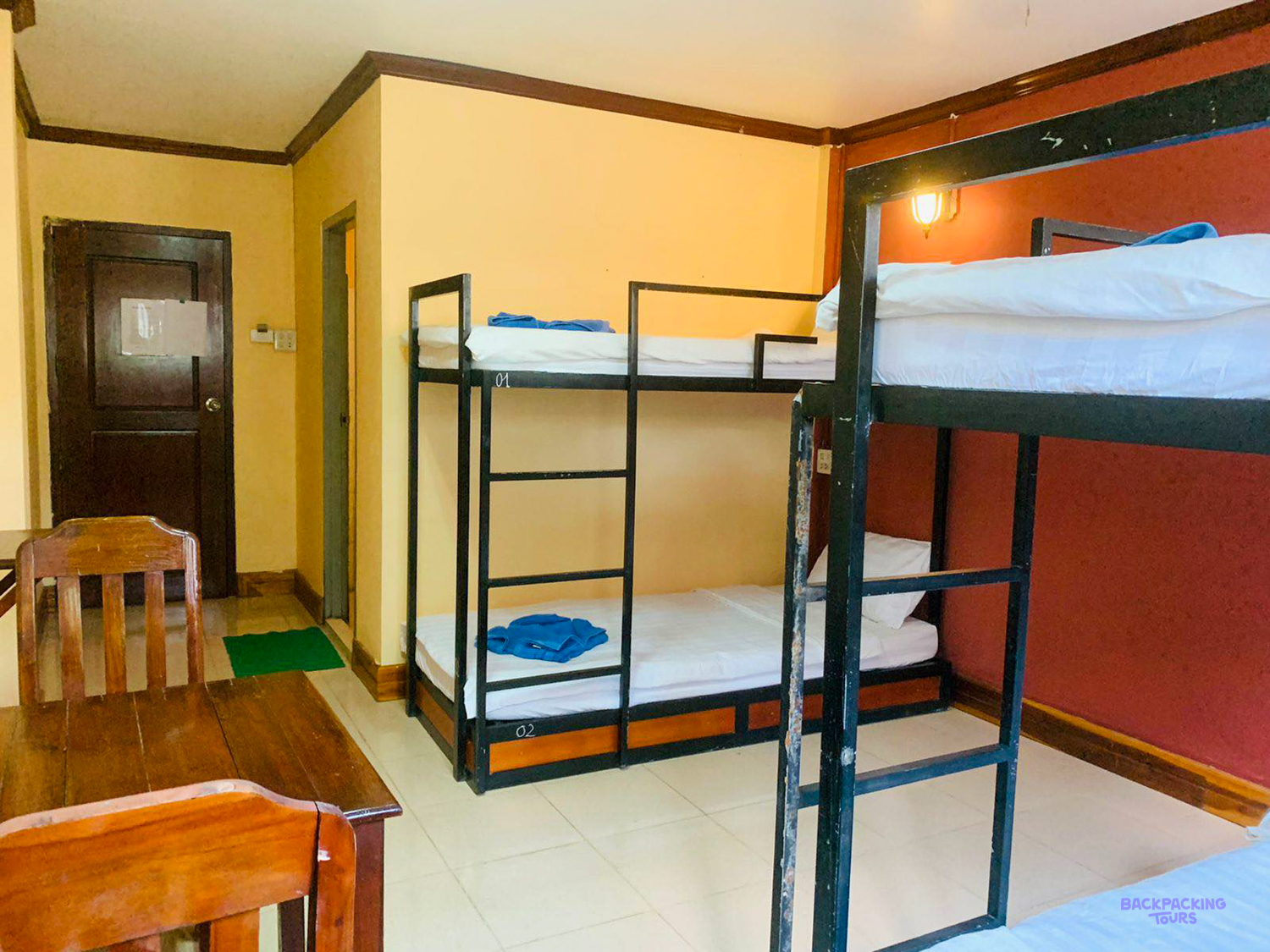 A shared room at the volunteer house with metal bunk beds, a wooden desk and chair.