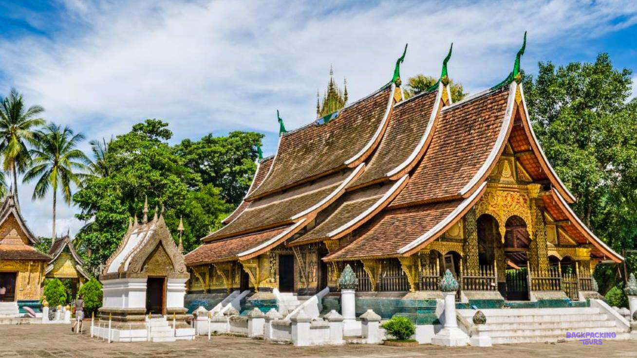 The sweeping tiered roofs of Wat Xieng Thong, Luang Prabang's best-known temple, under a blue sky.