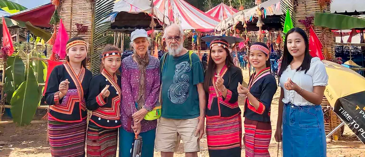Two volunteers pose with young Lao women in embroidered traditional dress at a colourful local festival.