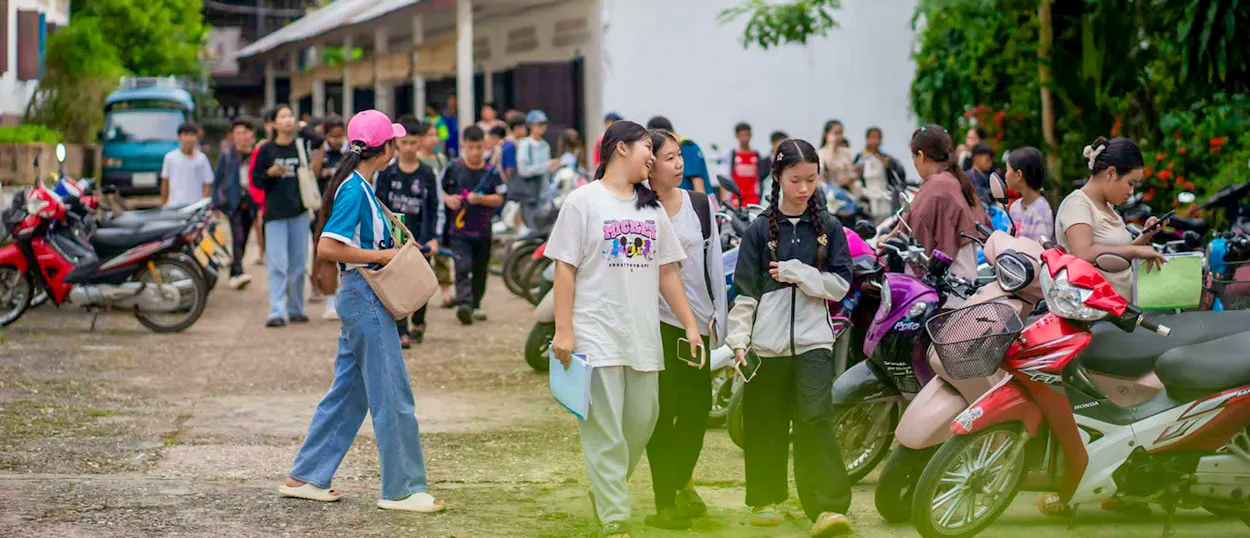 Students walk across a school yard lined with parked motorbikes in Luang Prabang.