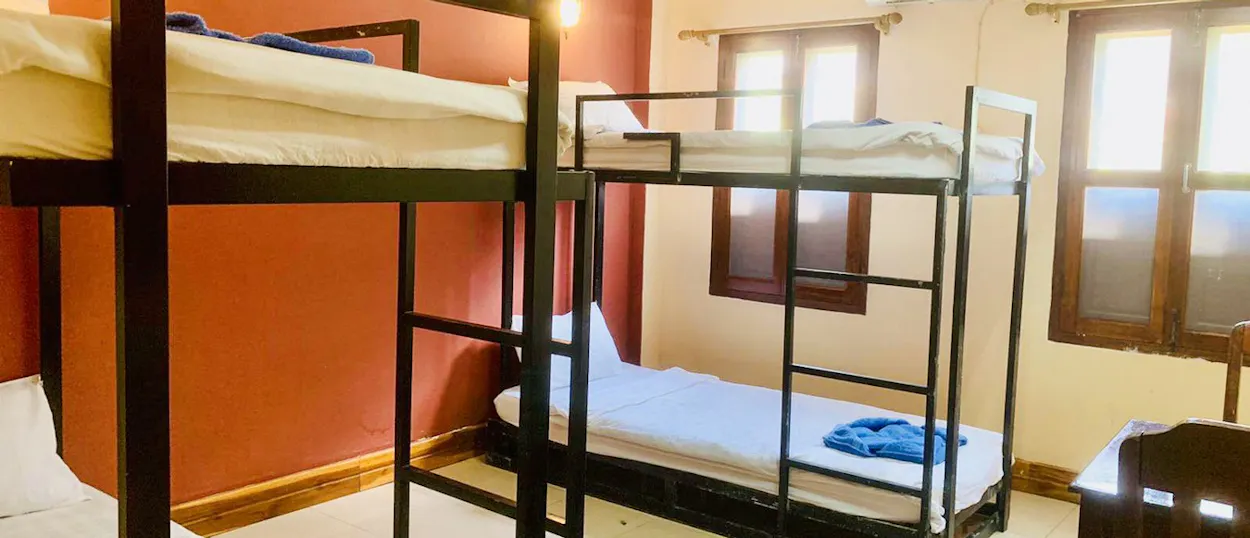 Two sets of bunk beds with fresh white sheets and folded towels in a shared volunteer room.