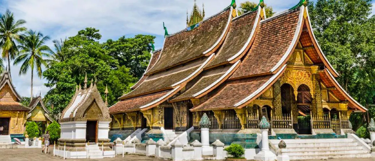 The sweeping tiered roofs of Wat Xieng Thong, Luang Prabang's best-known temple, under a blue sky.