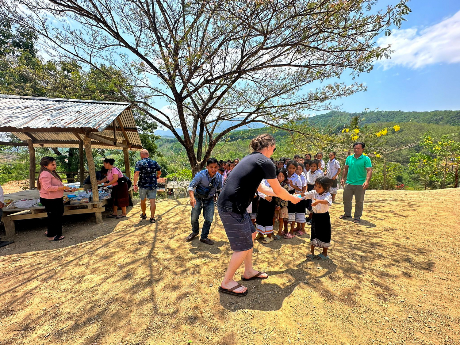 A volunteer hands school supplies to a line of pupils at a hillside village school.