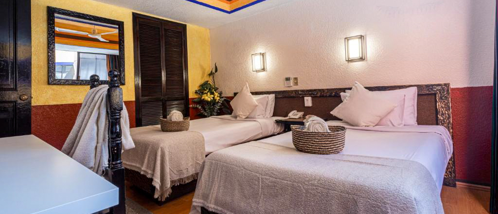 A comfortable hotel room in Mexico City featuring two beds and warm, traditional decor.