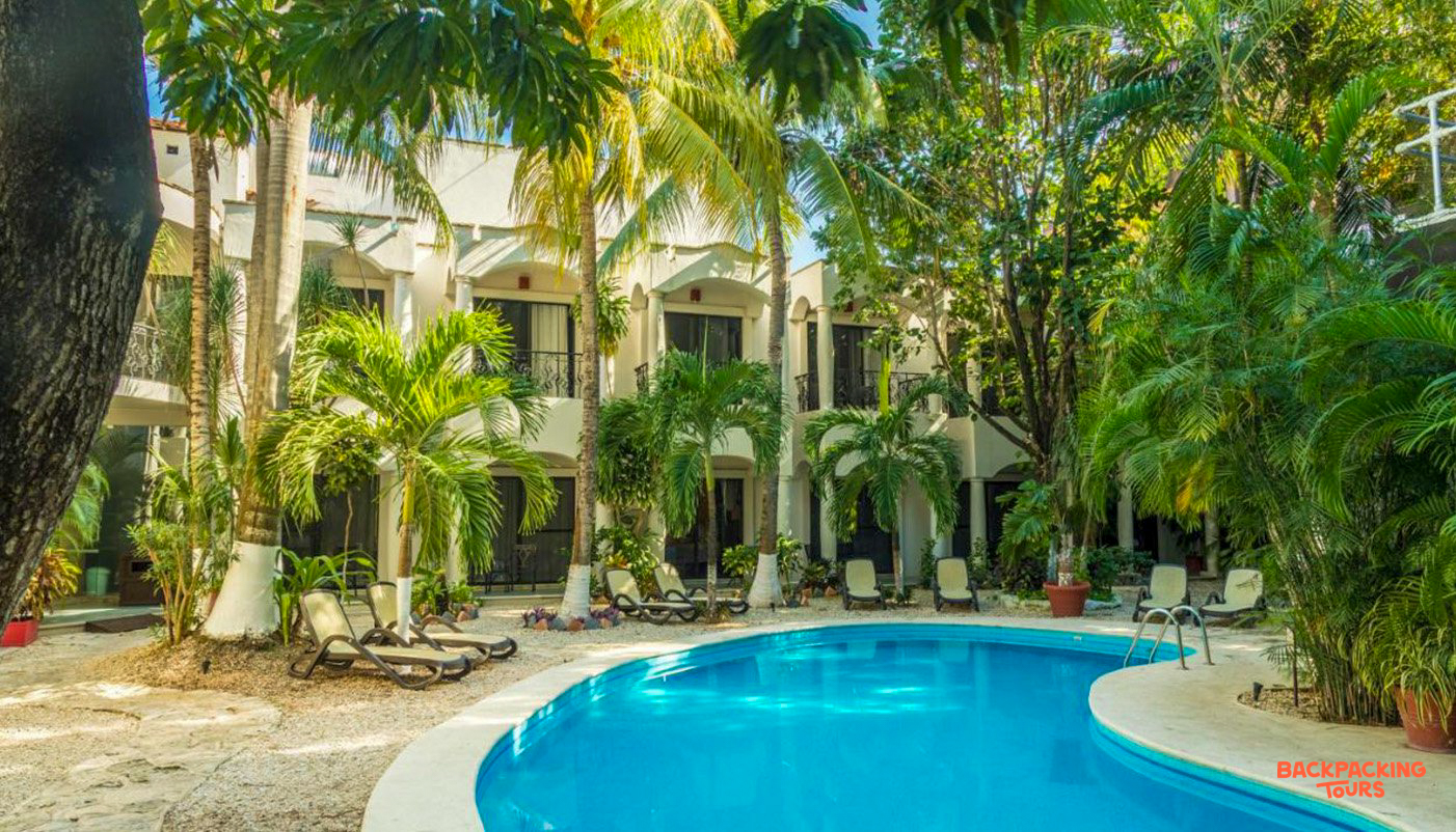 Relax by the inviting pool amidst lush palm trees at your boutique hotel in Playa del Carmen.