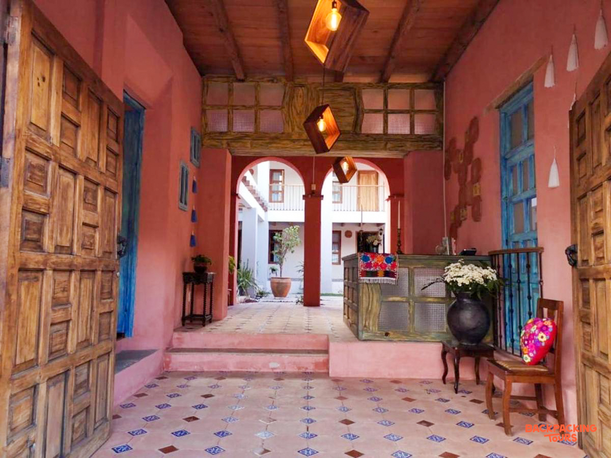 A vibrant pink hotel entrance in San Cristobal de las Casas, with patterned floor and a sunny courtyard.