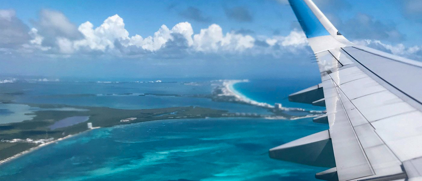 Stunning aerial view of Cancun's turquoise Caribbean waters, white beaches, and coastal resorts from an airplane.