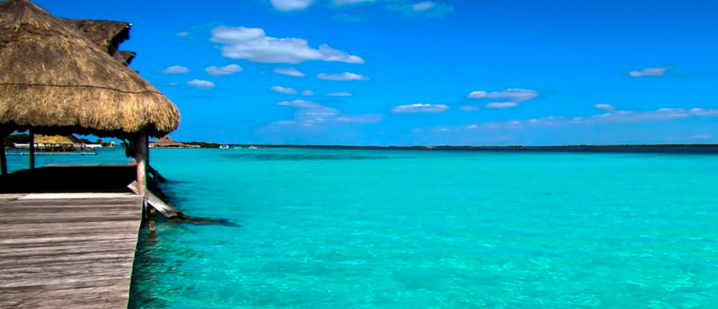 A tropical thatched hut and wooden pier over clear turquoise waters on Isla Holbox.