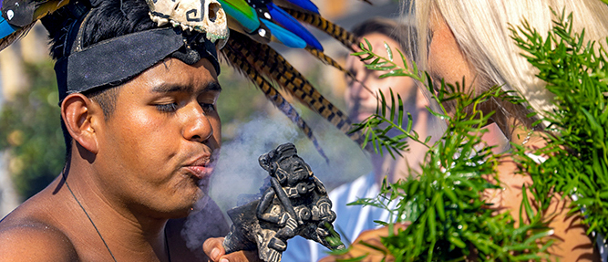 A man in a feathered headdress performs a traditional smoke ceremony in Tehuantepec, Mexico.