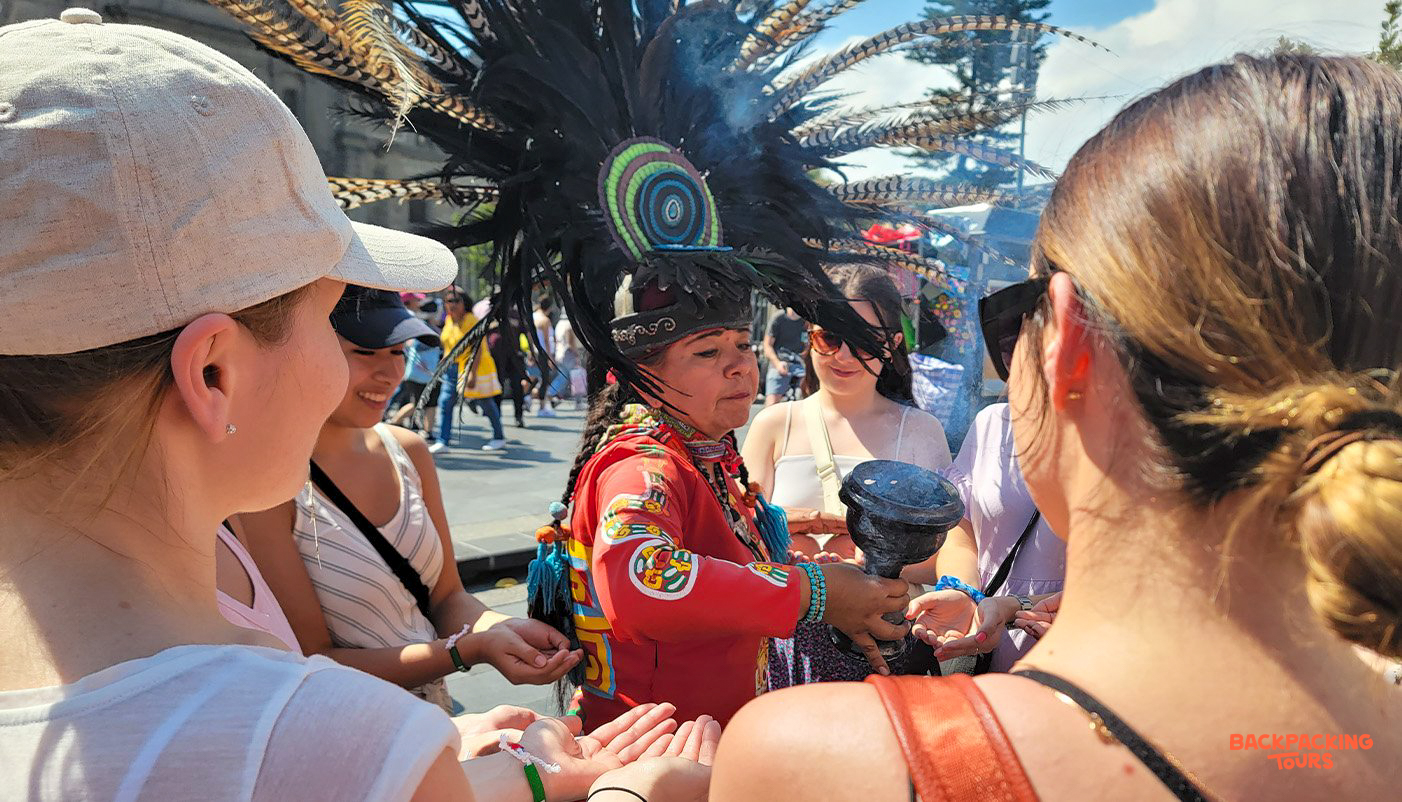 A traditional performer in Mexico City blesses tourists with incense during a cultural ceremony.