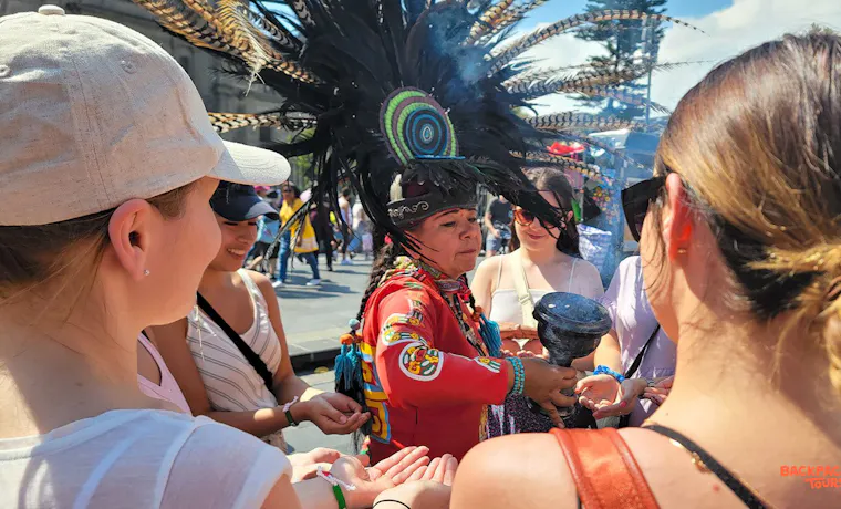 A traditional performer in Mexico City blesses tourists with incense during a cultural ceremony.