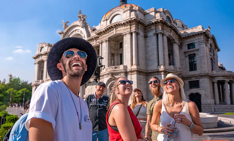 Happy backpackers gaze up at the beautiful Palacio de Bellas Artes in Mexico City.