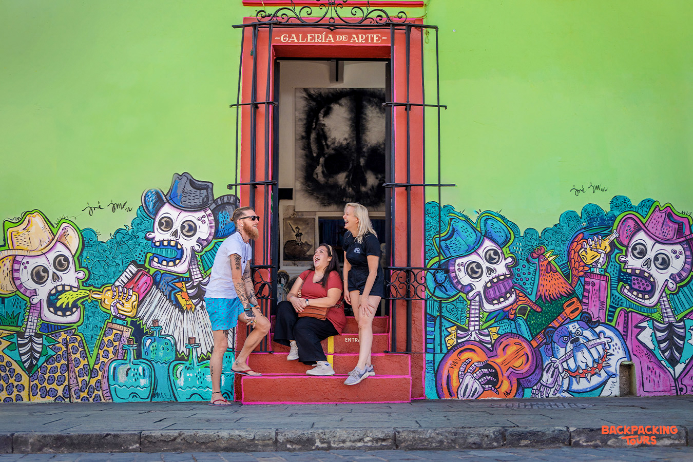 Three travelers enjoy the vibrant street art and a colorful gallery entrance in Mexico City.