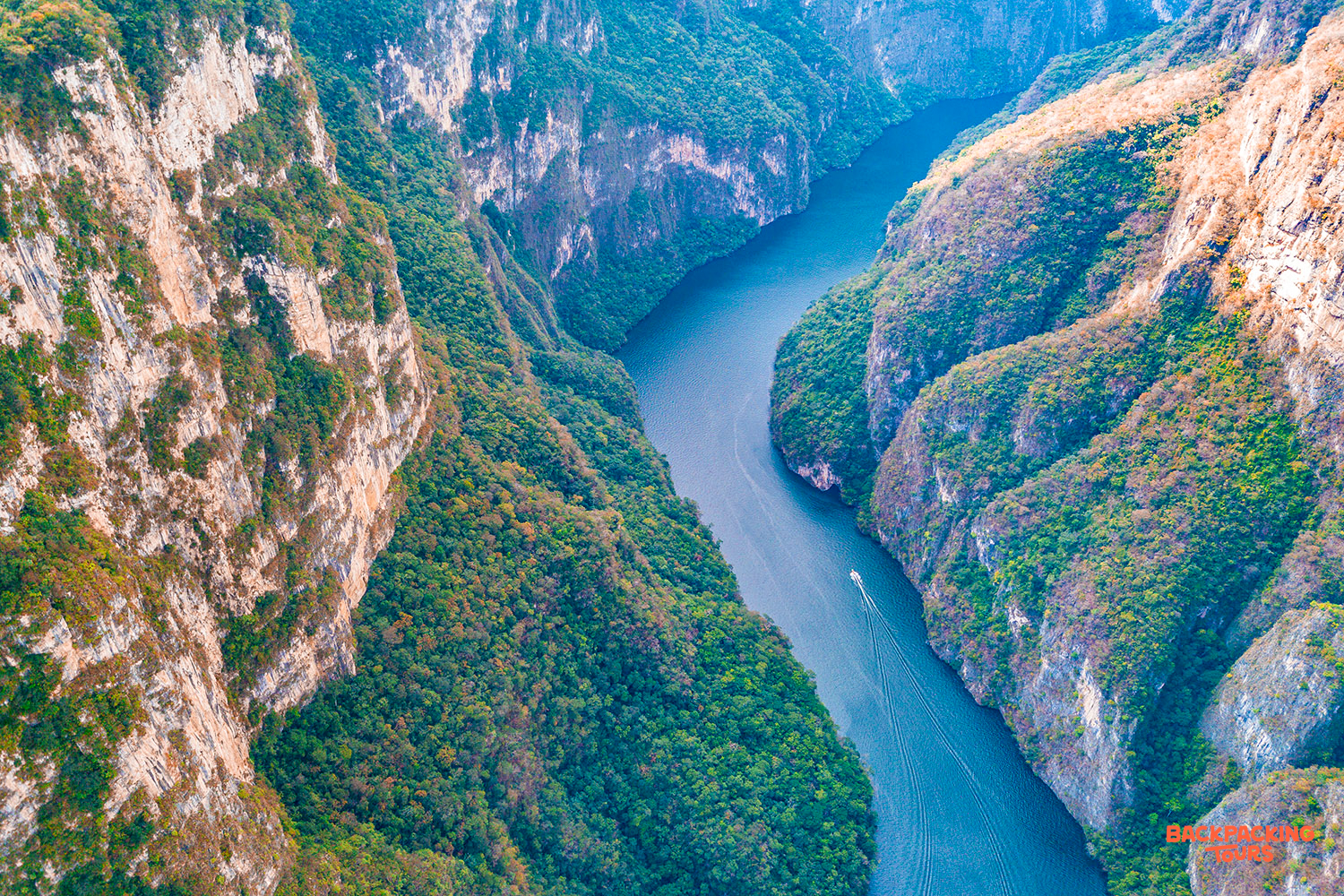 A boat cruises through the majestic Sumidero Canyon, surrounded by towering, jungle-covered cliffs in Mexico.
