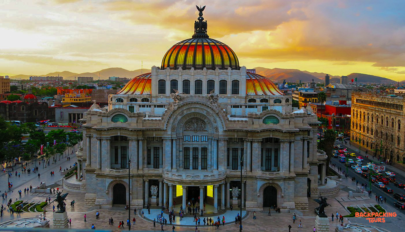 The magnificent Palacio de Bellas Artes in Mexico City glows under a vibrant sunset sky.