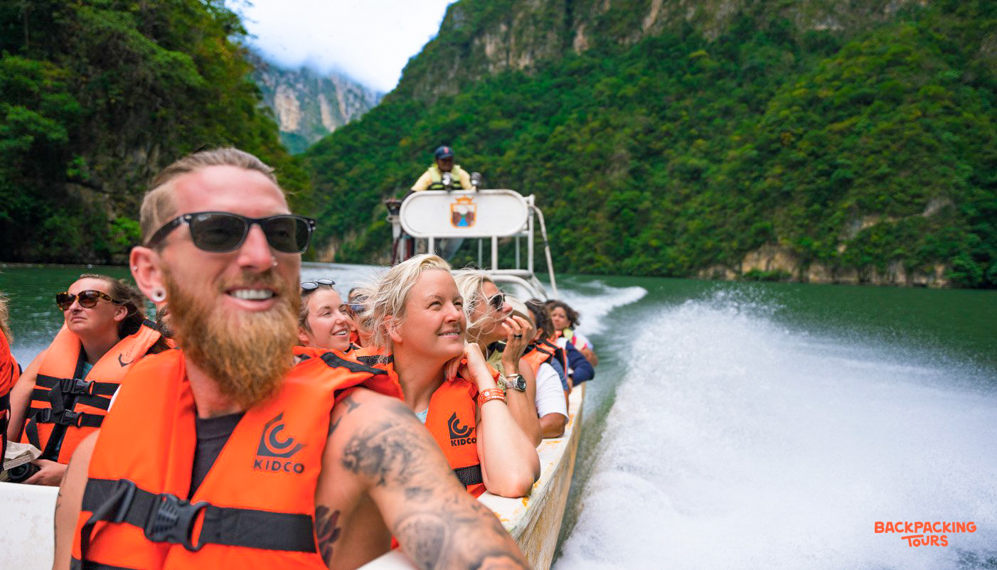 Happy backpackers enjoying a boat tour through the towering cliffs of Sumidero Canyon.