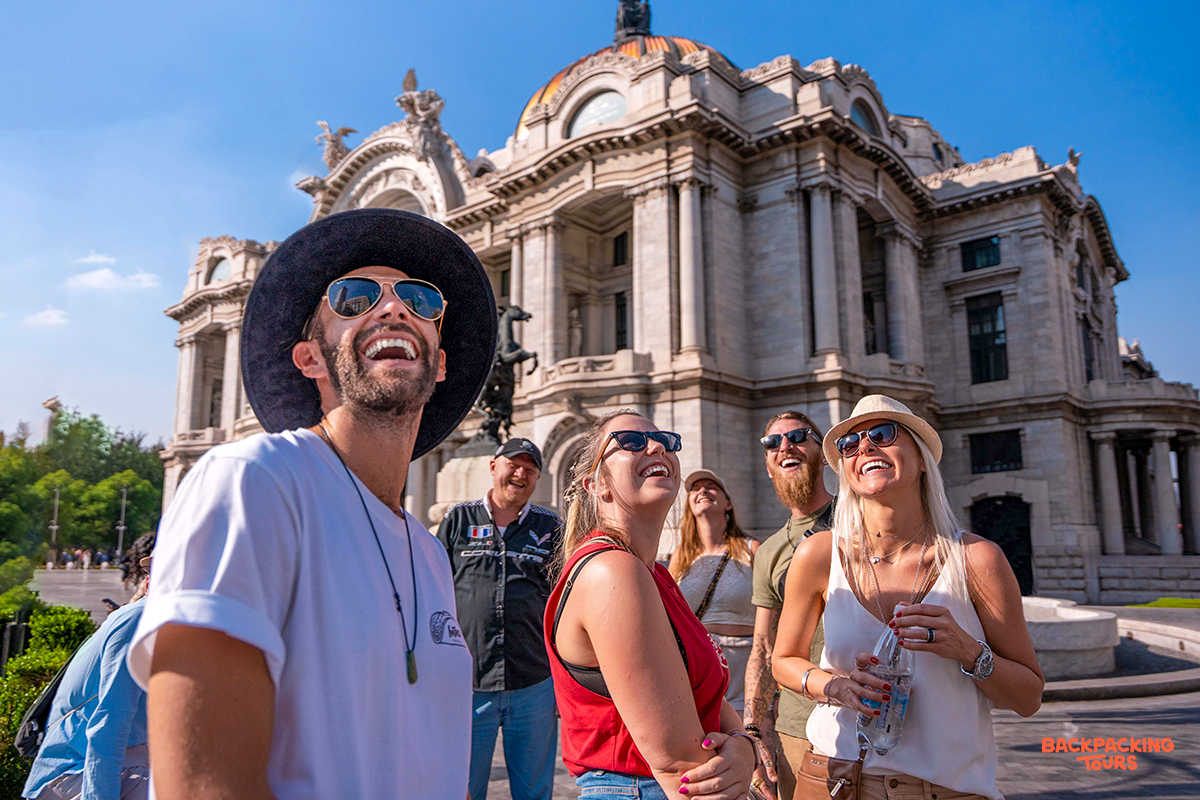 Happy backpackers gaze up at the beautiful Palacio de Bellas Artes in Mexico City.