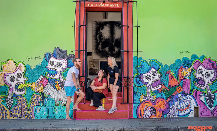 Three travelers enjoy the vibrant street art and a colorful gallery entrance in Mexico City.