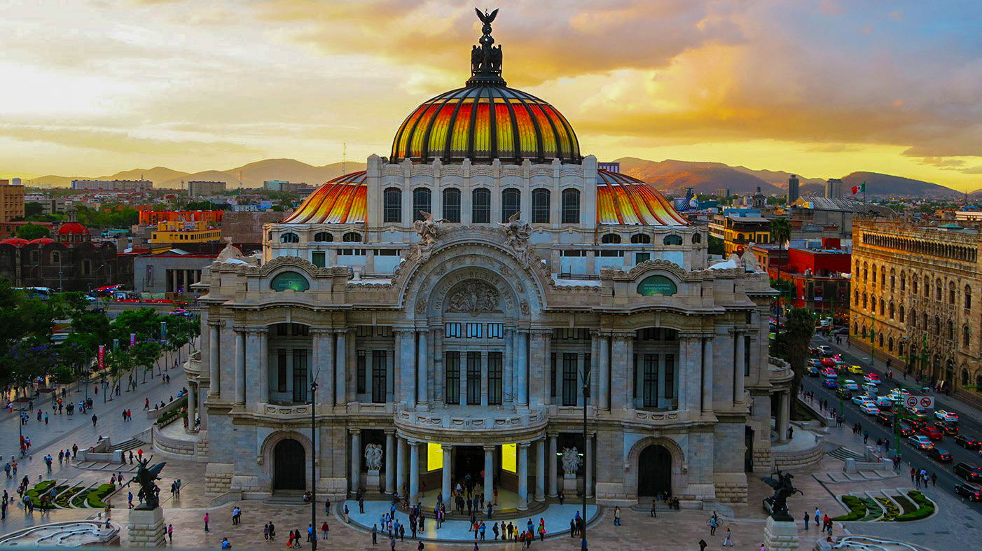 Grand Palacio de Bellas Artes with its colorful dome at sunset in bustling Mexico City.