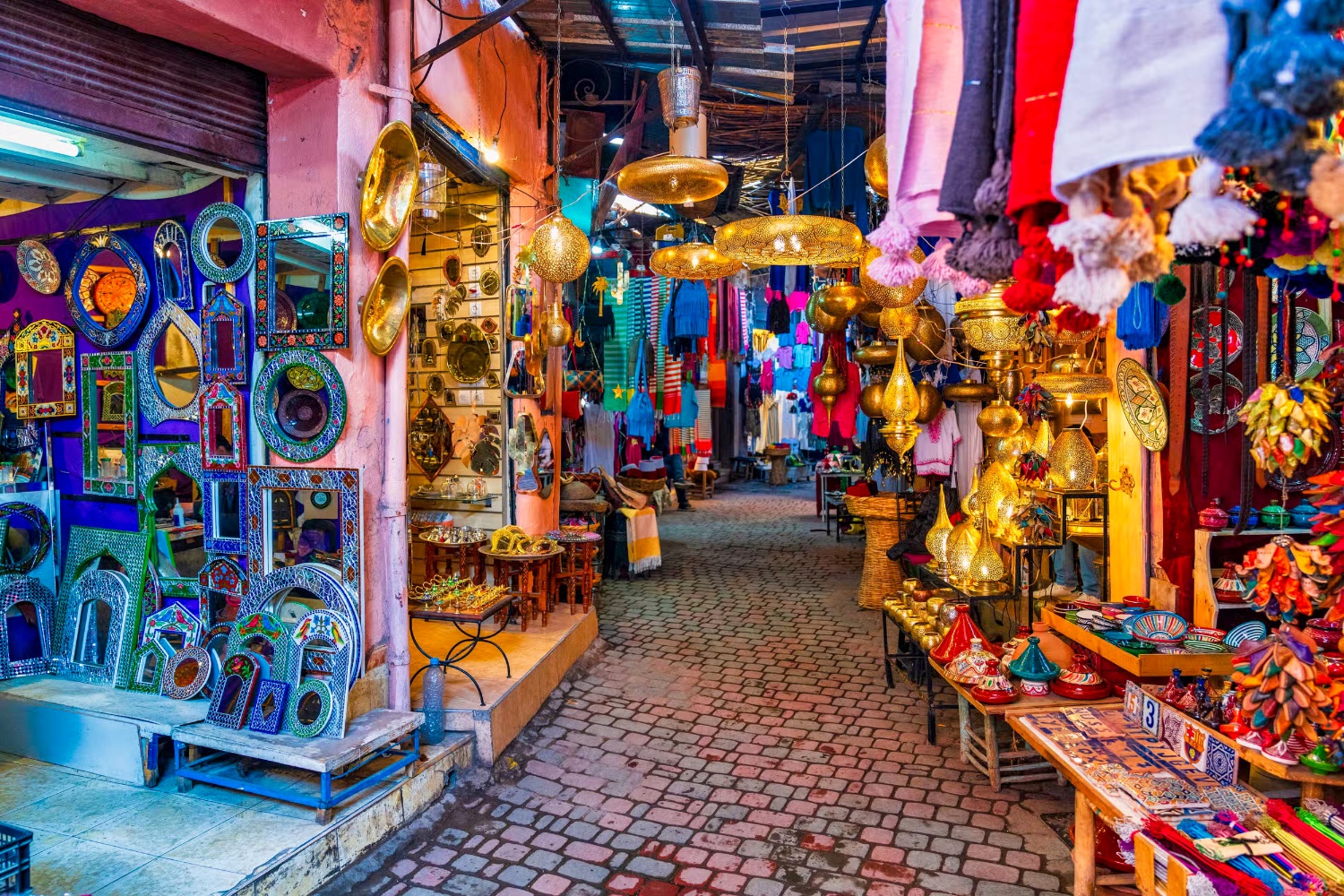 A vibrant Moroccan market alley filled with colorful lamps, handcrafted mirrors, and textiles.
