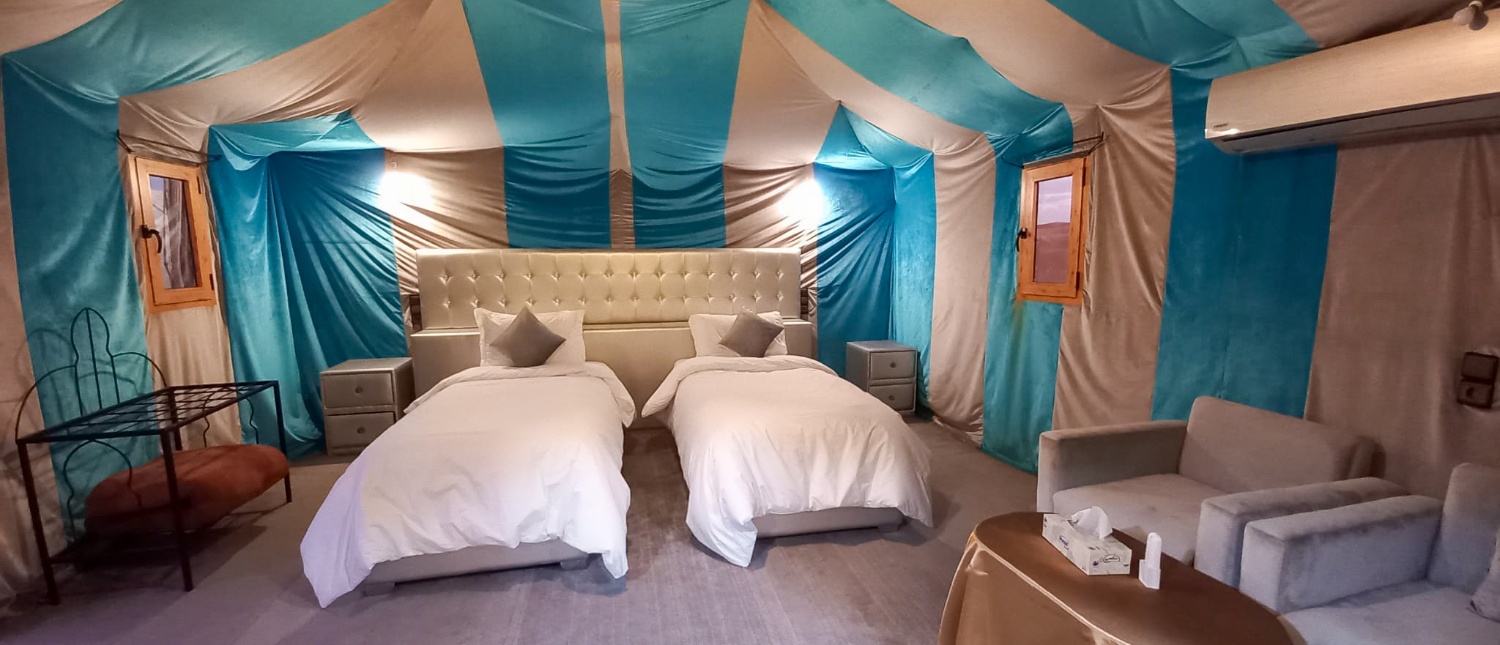 A luxurious glamping tent in Merzouga Desert with two beds and a comfortable seating area.