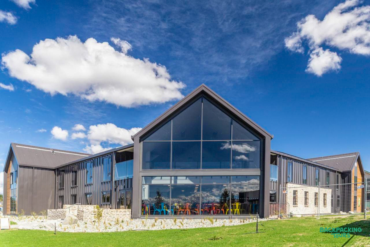 The modern YHA hostel building in Lake Tekapo features large glass windows and a striking A-frame design.