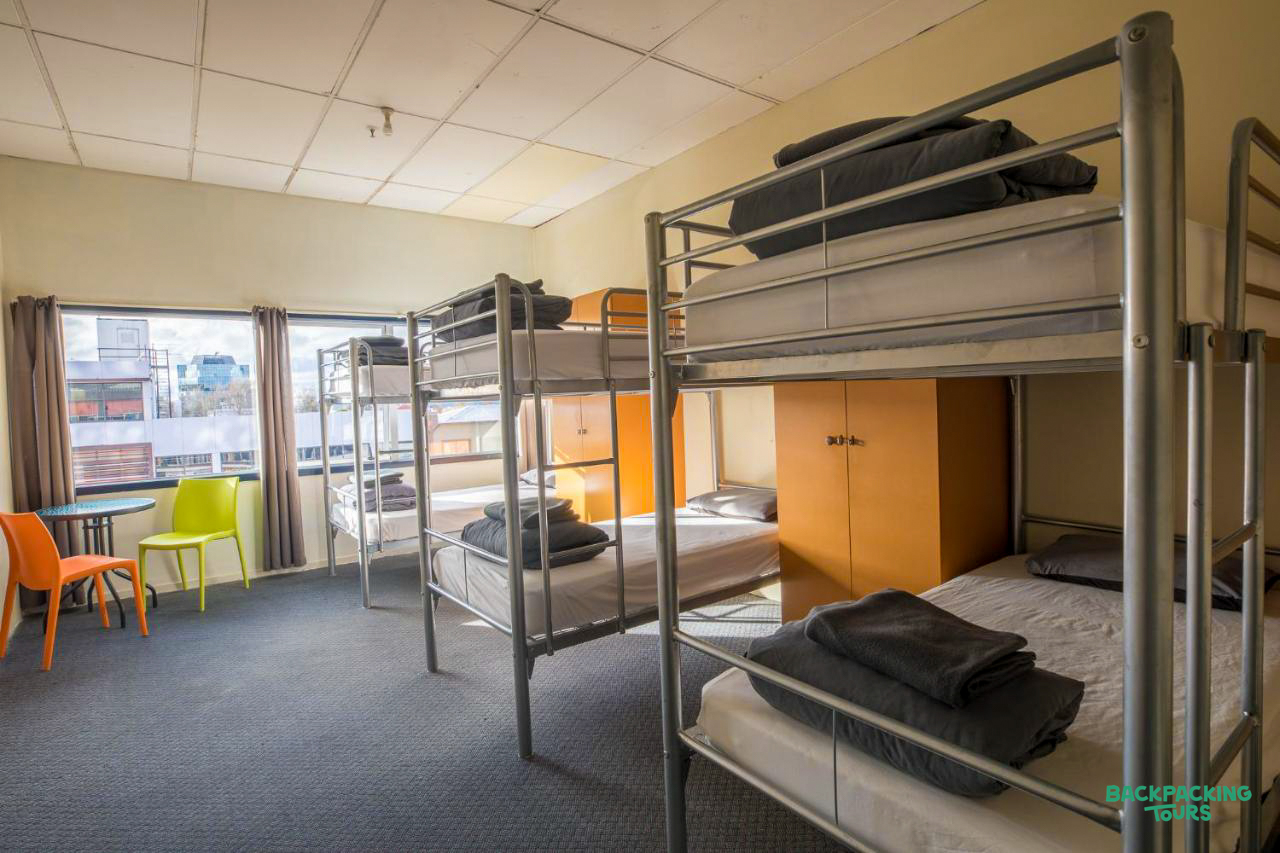 A clean and spacious hostel dorm room in Rotorua with multiple bunk beds and a window.