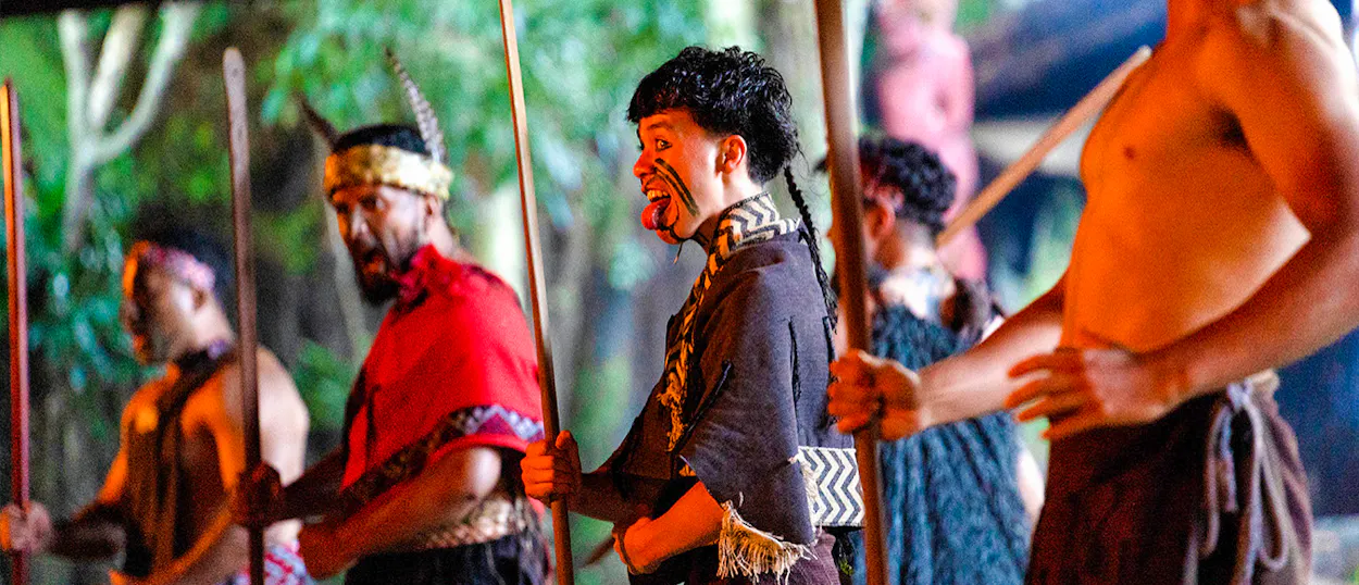 Māori men in traditional dress perform a powerful haka with spears in Rotorua, New Zealand.