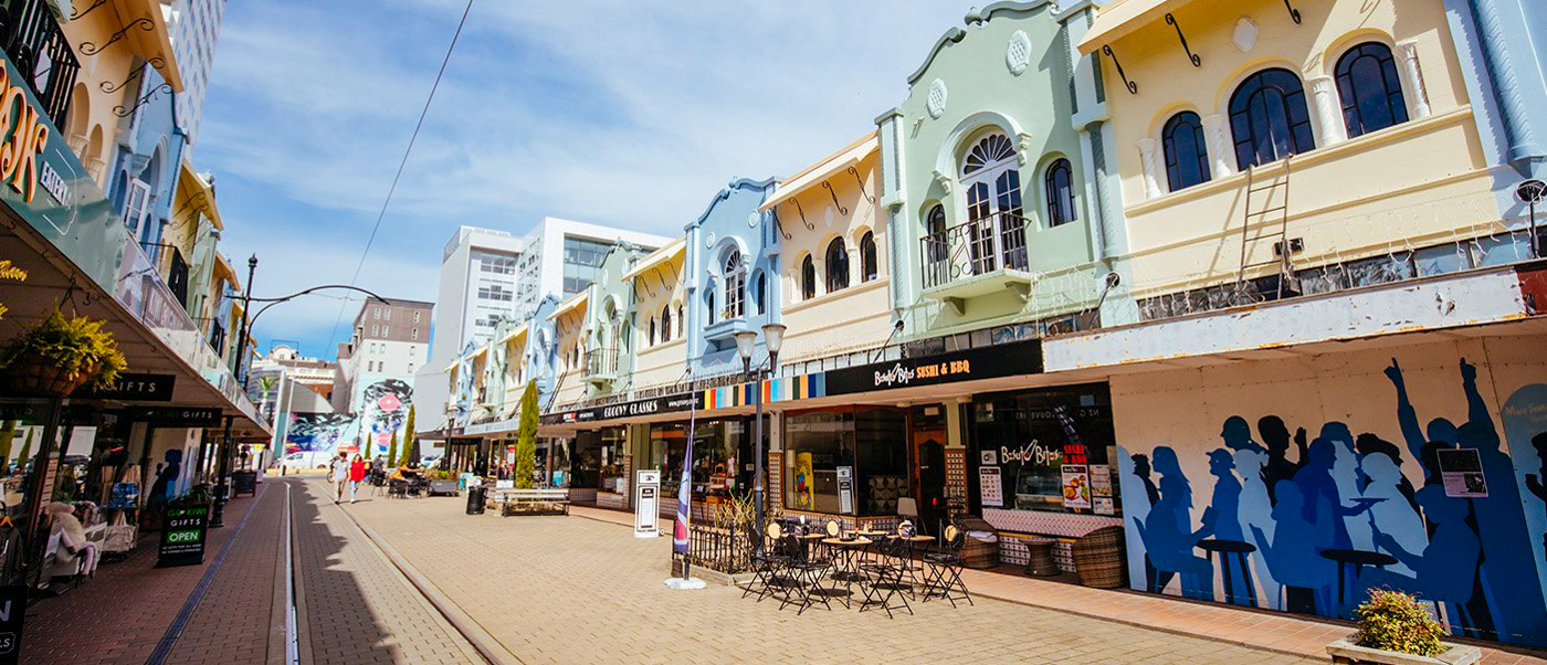 A bustling pedestrian street lined with colorful, ornate buildings and shops under a blue sky.