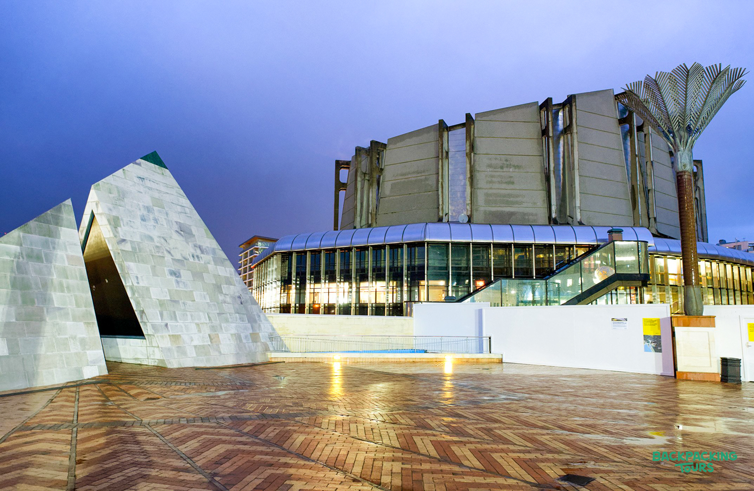 The striking architecture of Te Papa museum in Wellington at twilight, with a wet plaza.